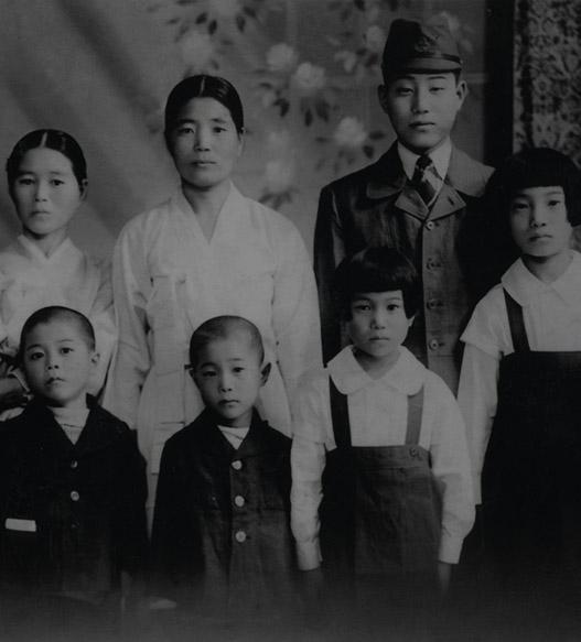 오래된 흑백사진 속에 어른 2명, 아이 5명이 있다.
